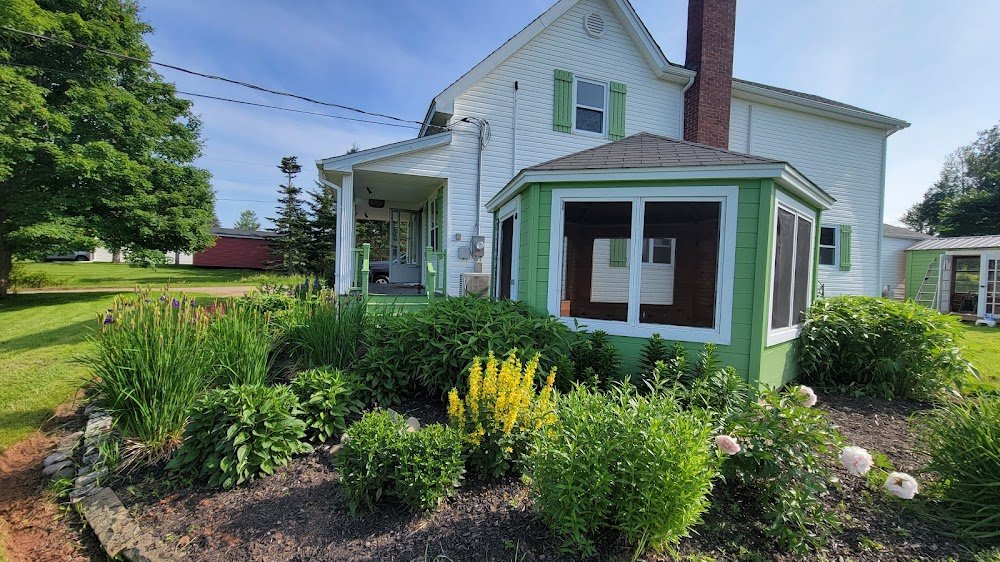Perennial garden wrapping around a green sunroom