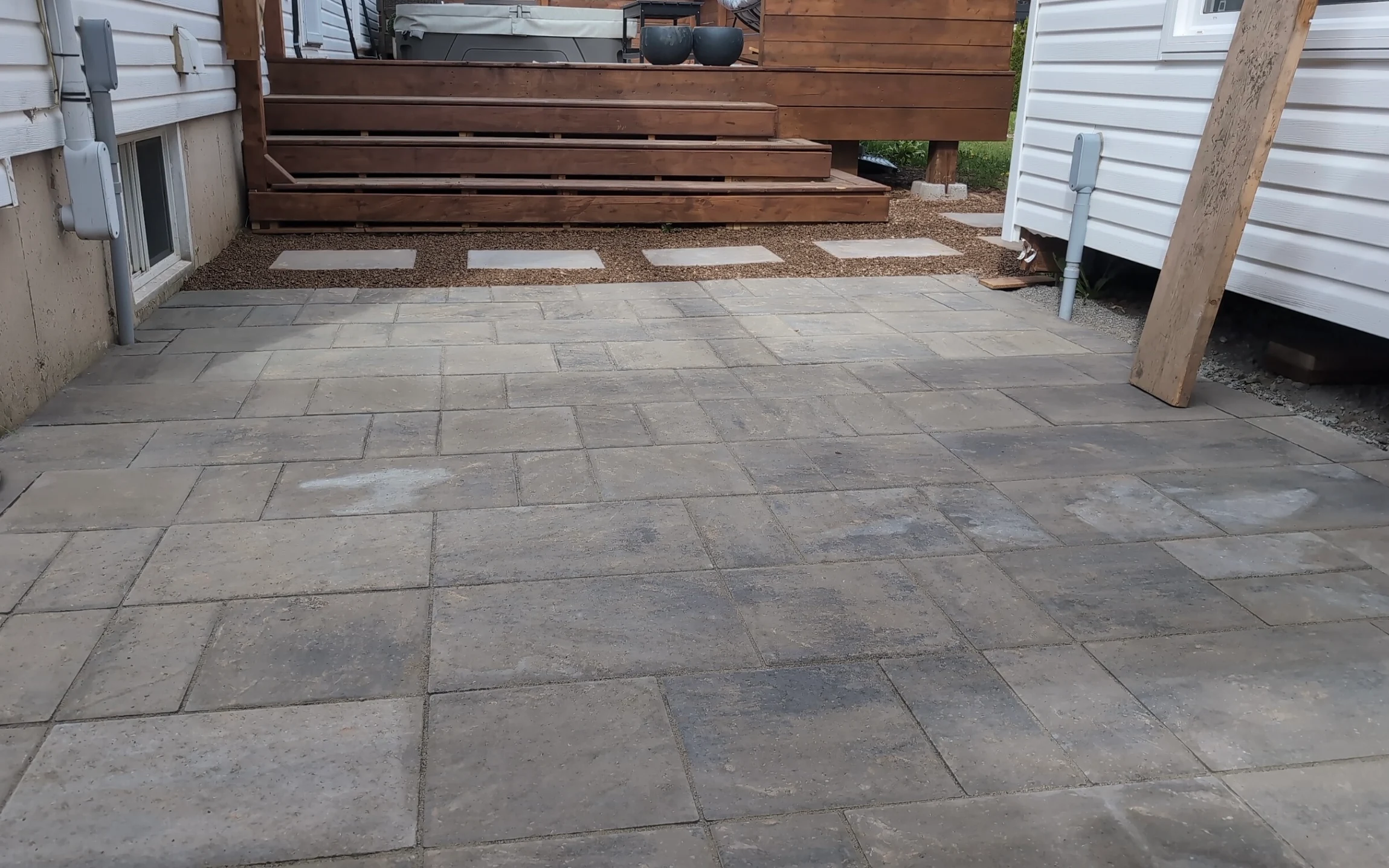 Interlock paver patio with square stepping stones below a wooden deck