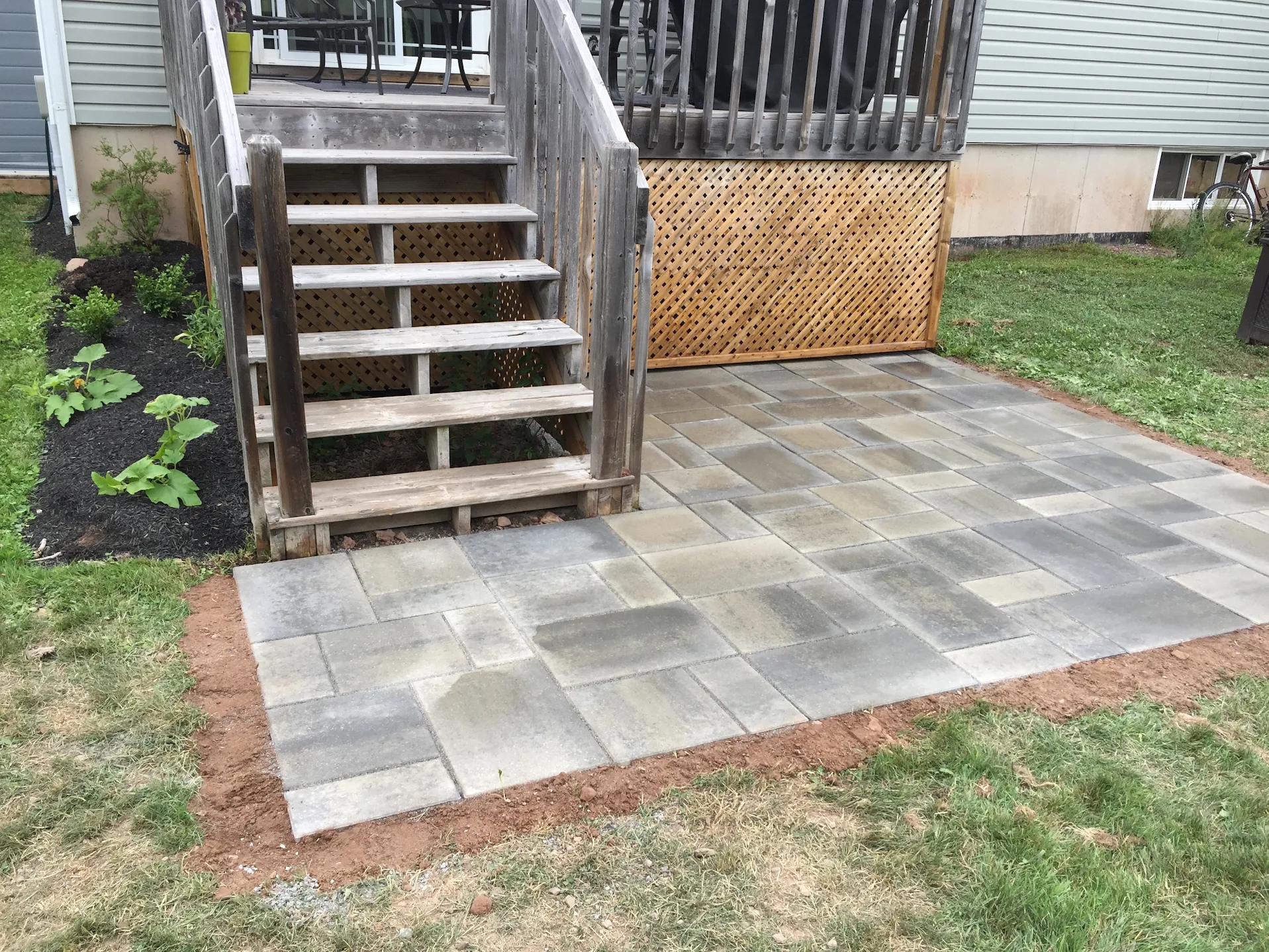 Multitone interlock paver landing beside wooden deck stairs