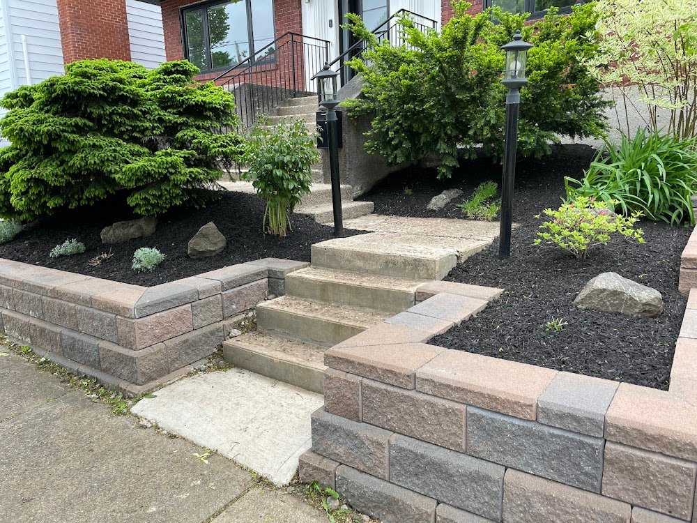 Front entrance steps bordered by fresh black mulch, shrubs and stone retaining walls